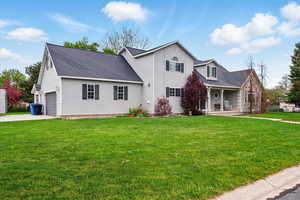 View of front of property with a porch, a front lawn, roof with shingles, and concrete driveway