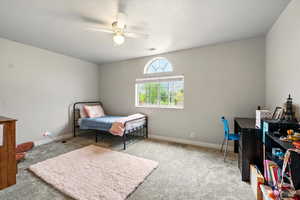 Carpeted bedroom featuring a ceiling fan and a textured ceiling