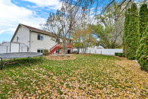 Rear view of house featuring a trampoline, stairs, a shed, and a fenced backyard