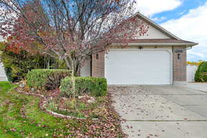 View of front of property featuring brick siding, driveway, an attached garage, and roof with shingles
