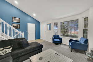 Carpeted living room with stairs, recessed lighting, and high vaulted ceiling