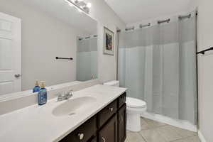 Full bathroom with light tile patterned floors, a shower with shower curtain, and vanity