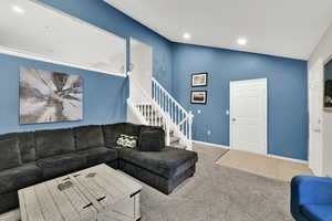Carpeted living area with tile patterned floors, recessed lighting, stairs, and high vaulted ceiling
