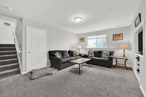 Carpeted living area featuring stairs and a textured ceiling