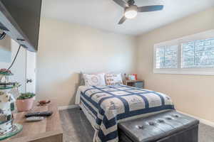 Carpeted bedroom featuring a ceiling fan and baseboards