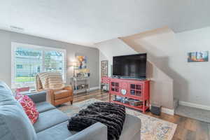 Living room with wood finished floors, a textured ceiling, and stairs