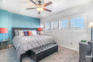 Carpeted bedroom featuring multiple windows and a ceiling fan