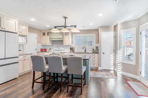 Kitchen featuring white appliances, a kitchen island, healthy amount of natural light, a kitchen breakfast bar, and recessed lighting