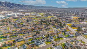 Aerial view of property and surrounding area featuring a mountainous background and nearby suburban area