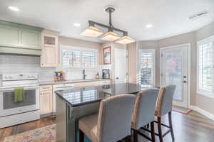 Kitchen featuring white appliances, pendant lighting, a breakfast bar, backsplash, and a kitchen island