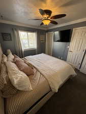 Bedroom with ornamental molding, a textured ceiling, ceiling fan, and carpet flooring