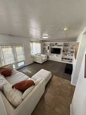 Carpeted living room featuring a textured ceiling and tile patterned flooring