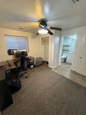 Office space with a textured ceiling, light carpet, and a ceiling fan