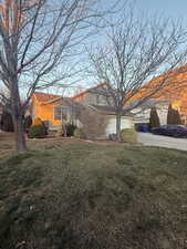 View of front facade with a front yard, a garage, and driveway