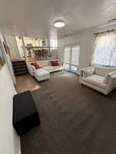 Living room with carpet flooring, a textured ceiling, french doors, and stairway