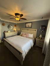Bedroom featuring dark colored carpet, a ceiling fan, a textured ceiling, and ornamental molding