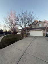View of property exterior with concrete driveway, a garage, a lawn, stucco siding, and stone siding