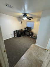 Carpeted office space featuring tile patterned floors, a textured ceiling, and a ceiling fan