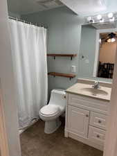 Full bathroom featuring a shower with curtain, vanity, a textured ceiling, a ceiling fan, and dark tile patterned floors