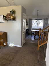 Dining area with carpet floors, stairs, and a chandelier