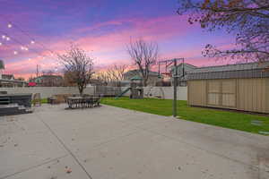 Fenced backyard featuring a playground, a shed, a patio area, and outdoor dining area