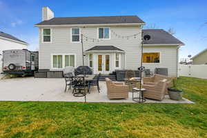 Rear view of property featuring a patio, a shingled roof, french doors, a chimney, and an outdoor fire pit