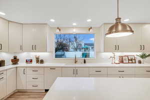 Kitchen featuring light stone counters, light wood-style floors, decorative light fixtures, recessed lighting, and white cabinetry