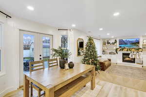 Dining room featuring french doors, a glass covered fireplace, light wood finished floors, recessed lighting, and built in shelves