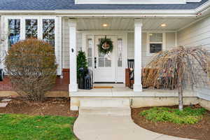 Property entrance with a shingled roof and covered porch