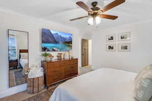 Carpeted bedroom featuring ornamental molding and ceiling fan