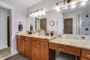Full bath featuring double vanity, a shower stall, and light tile patterned flooring