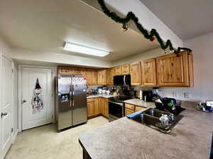 Kitchen featuring appliances with stainless steel finishes, light countertops, brown cabinetry, a textured ceiling, and light floors