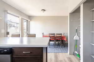 Kitchen featuring dark brown cabinetry, light countertops, dishwasher, and light wood-style floors