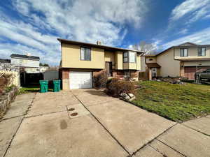 Split foyer home featuring brick siding, concrete driveway, and an attached garage