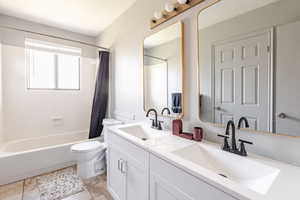 Full bathroom with shower / bath combination with curtain and double vanity