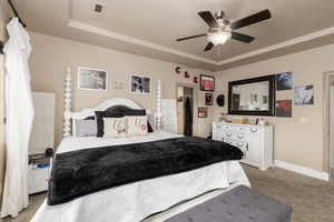 Bedroom featuring light carpet, a raised ceiling, a textured ceiling, and a ceiling fan