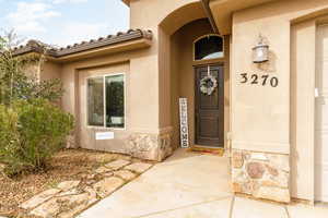 View of exterior entry with stucco siding, stone siding, and a tile roof