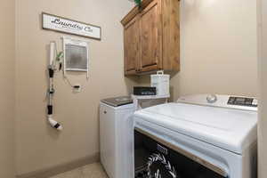 Laundry room featuring cabinet space, separate washer and dryer, light tile patterned flooring, and a wall mounted air conditioner