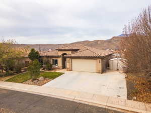 Mediterranean / spanish-style house with a mountain view, stucco siding, concrete driveway, a garage, and a front lawn