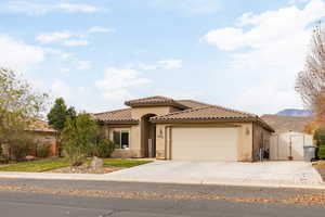 Mediterranean / spanish house featuring concrete driveway, stucco siding, an attached garage, stone siding, and a tile roof
