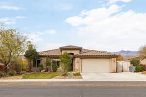 Mediterranean / spanish-style home featuring stucco siding, a tile roof, concrete driveway, and an attached garage