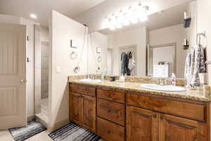 Bathroom featuring double vanity, walk in shower, and light tile patterned floors