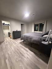 Bedroom with a walk in closet and light wood-type flooring