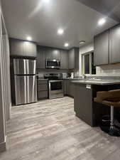 Kitchen featuring appliances with stainless steel finishes, light wood-type flooring, a breakfast bar area, and recessed lighting