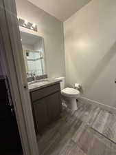 Bathroom with vanity, dark wood-type flooring, and tiled shower