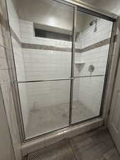 Bathroom with a shower stall and wood finished floors