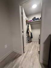 Walk in closet with light wood finished floors