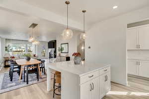 Kitchen featuring open floor plan, recessed lighting, white cabinetry, a kitchen island, and pendant lighting