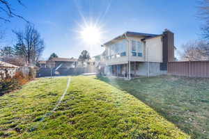 Rear view of property with a fenced backyard, a chimney, stairway, and a sunroom