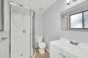 Full bathroom with healthy amount of natural light, vanity, light tile patterned floors, and a stall shower
